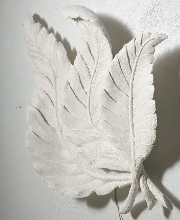 Boldly hand-carved trophy of three large leaves joined at the stems. Lighting hidden within flows upwards and through gaps between the overlapping leaves. Heavy gesso paint gives the effect of plaster.  Both the period and style of Dorothy Draper's