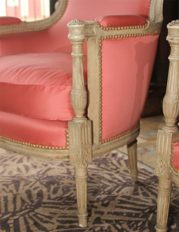 Pair of attractive painted French Louis XVI style bergeres with light pink silk upholstery. Stamped Jansen. Fine white distressed wood finish. New fabric, welts, springs and fully tacked in front and back.
