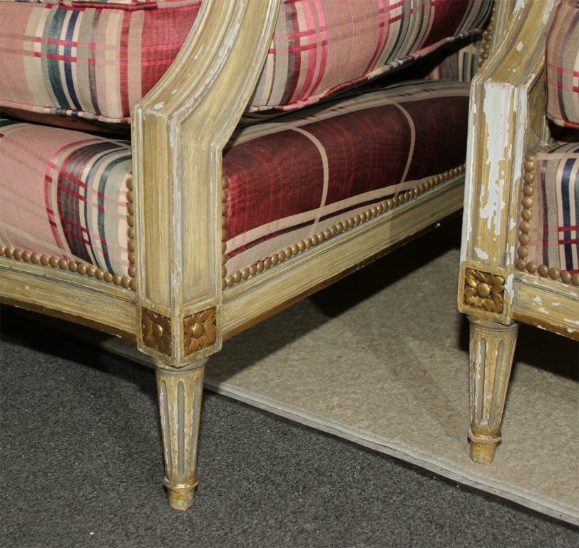Single polychromed and gilded Louis XVI style bergere chair. Stamped Jansen. In a finely carved white distressed and gilt highlighted frame. In new upholstery with new springs, welts and stuffing.