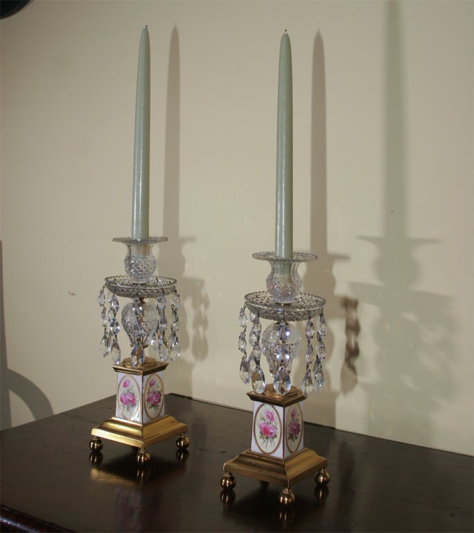 An elegant pair of George III gilt brass and cut crystal candlesticks with floral and gilt decorated square porcelain bases. English, circa 1810.
