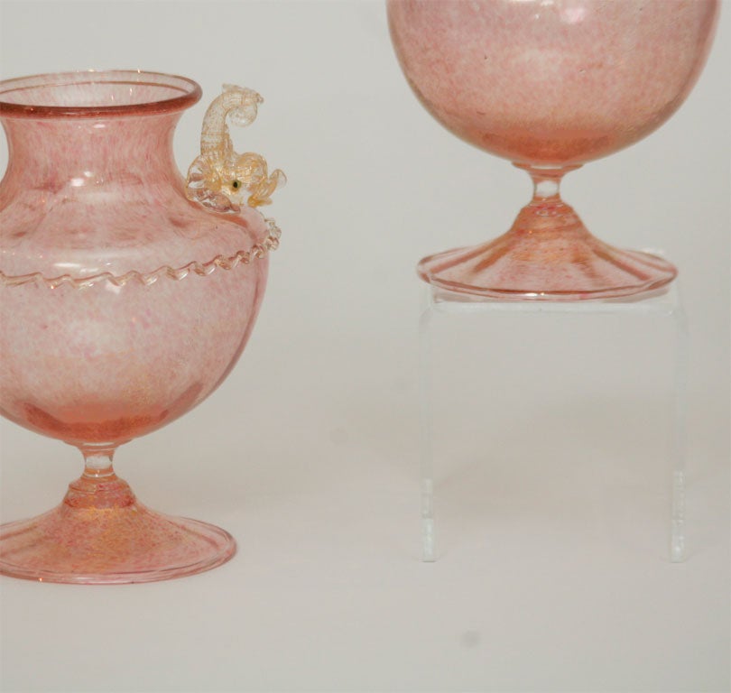 This is a wonderful and rare pair of hand blown figural vases. The mottled pink glass is filled with gold leaf inclusions, applied rigaree is like icing on a cake and 2 dolphin 