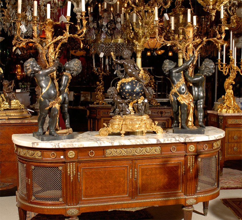 A superb pair of five-light gilt and patinated bronze electrified candelabra featuring cherubs supporting a naturalistic branch type candelabra signed 