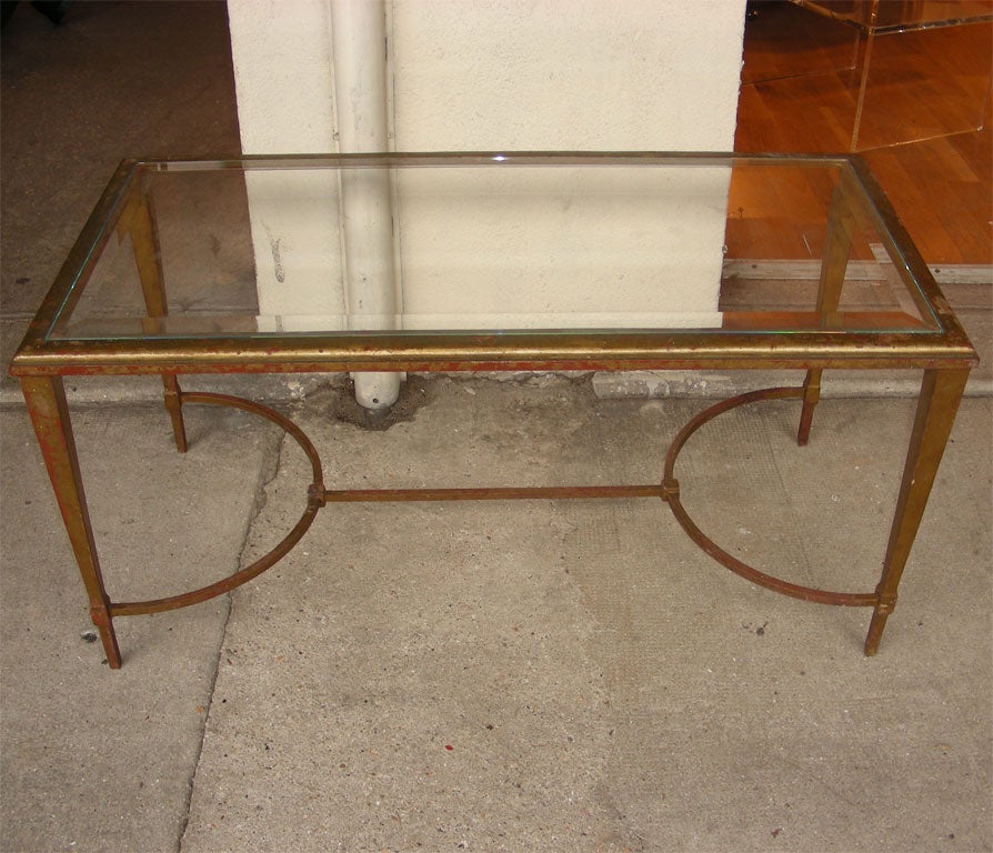 1960s coffee table by Gilbert Poillerat with top in bevelled glass and base in gilt wrought iron.