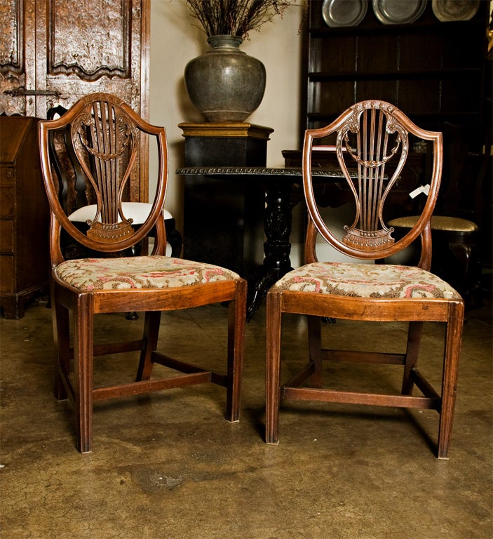 A pair of George III mahogany shield-back chairs, each with finely carved back with lyre, the drop-in seat on a serpentine seatrail resting on square molding chamfered legs with 