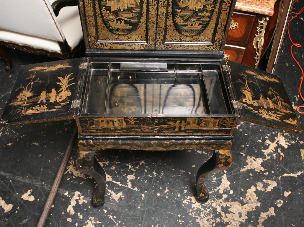 First quarter 19th century, the scrolled pediment above a pair of doors decorated with oriental landscapes and figures.  The interrior containing a series of drawers centered by a mirrored door, the lower case with side-hinged lids opening to a well