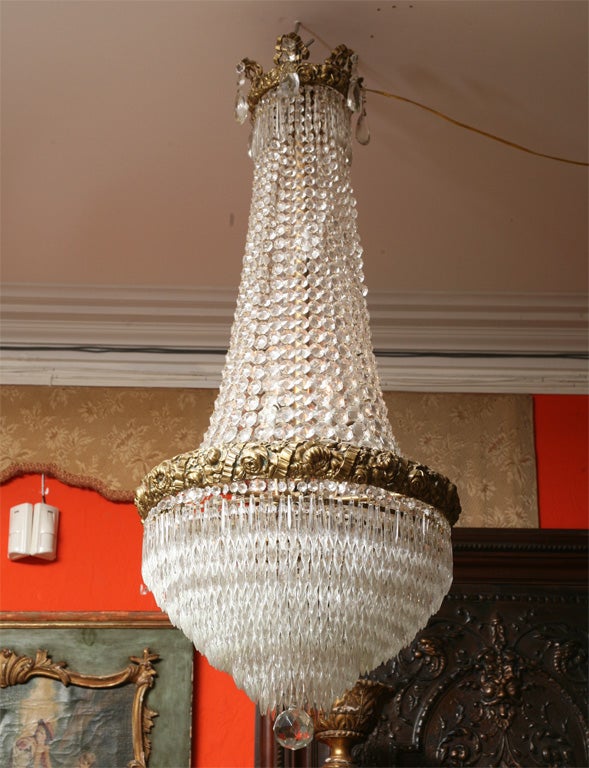 With masses of crystal chains and hanging graduated prisms form the elegant basket shape of this fixture, with interior lights.  The beautiful ormolu collar at the top in the form of roses with a second collar around the middle and terminated with a