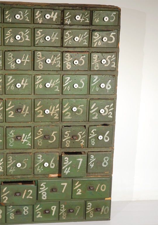 One of a kind, large two piece American general store bolt bin with 87 drawers.  Original green surface with original white hand painted numbers and original porcelain and iron pulls. Some of the drawers are deeper than the case to accomodate