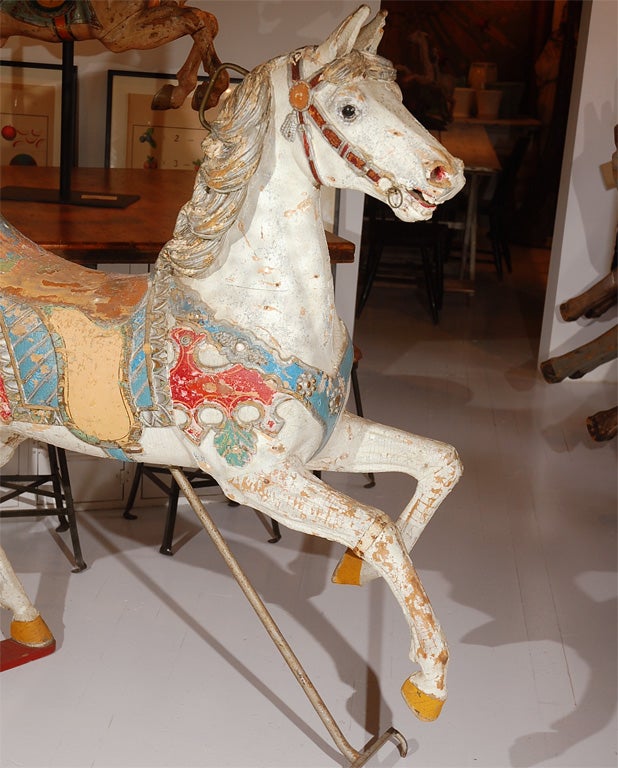 Superbly carved carousel horse found at an amusement park in the Northeastern United States. Most likely German carved. Incredible paint surface and original jewels. Has a colorful carved parrot head on the back of the saddle. Lifelike glass eyes