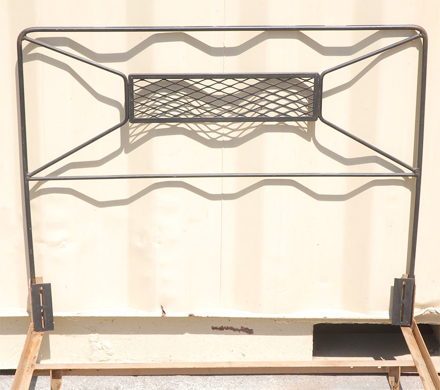 Pair of twin beds, wrought iron headboards with lattice design in center.