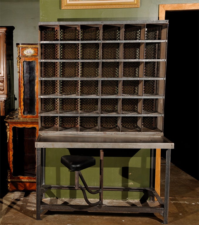 French brushed steel postal sorting desk with 36-compartment Cartesian grid storage section and naughehyde swing-away seat.  After original design by Roux Spritz, circa 1930