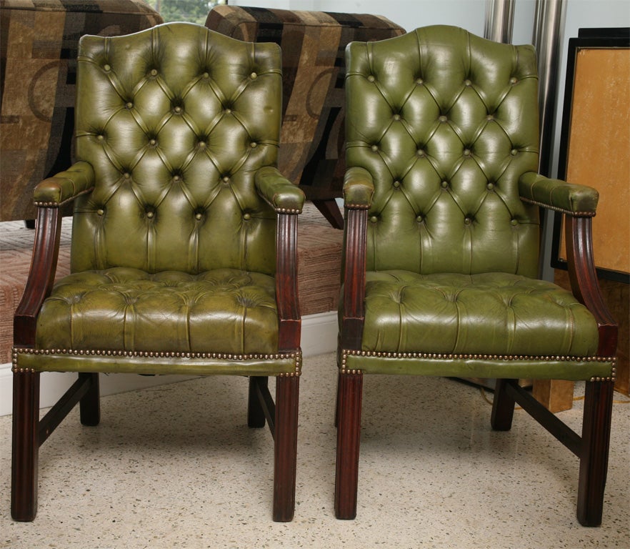 The arched back and seat with apple green tufted leather, the arms and legs in dark walnut.