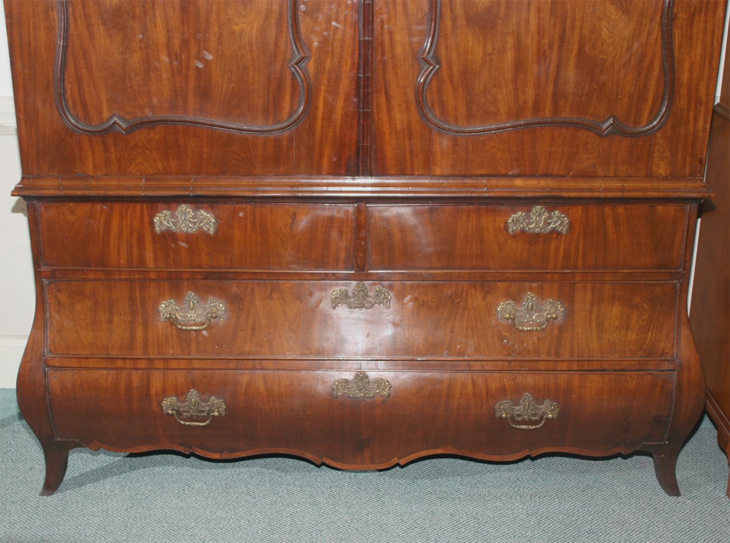 Dutch mahogany linen press having shaped doors with applied moldings; Bombe base with four-drawer (two over two). The waved, arching pediment sets the tone for the lines below. Beautifully grained mahogany is used throughout this magnificent and