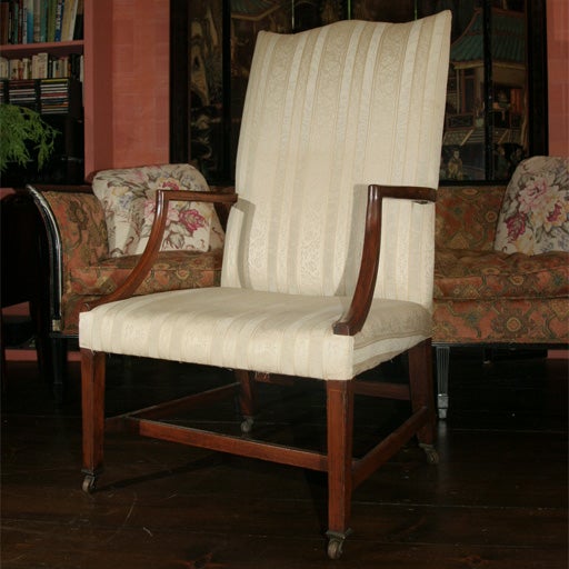 A reverse serpentine crested lolling (arm) chair on casters, with mahogany arms, legs with fine string inlays, and stretchers.