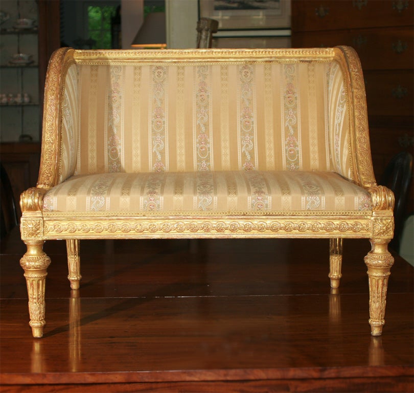 In the style of Louis XVI, a finely detailed hand-carved and gilded banquette, with<br />
its makers label; proportioned for a child.  Recent silk upholstery.  A decorative<br />
curiosity, or possibly a lounge for a small 'chien'.