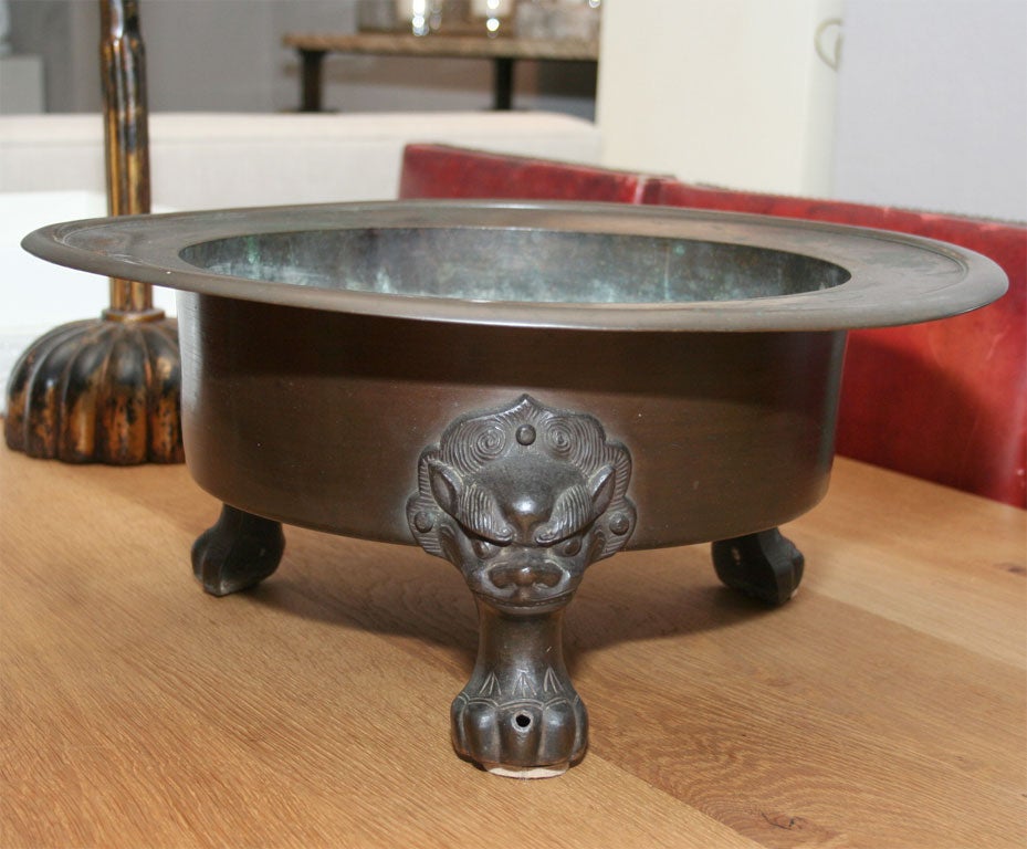 Bronze bowl with three lion head feet.