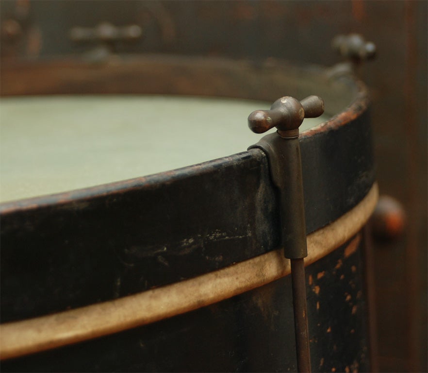 Antique drum on a black iron base and glass insert covering the parchment drum surface.