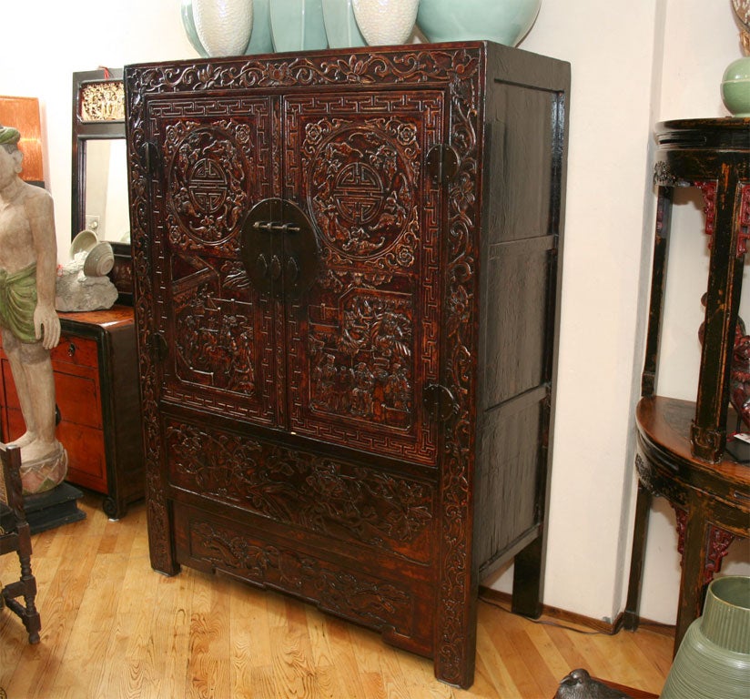 Fine Chinese 18th century Qing Dynasty highly carved front wedding cabinet or armoire depicting carved relief court yards scenes and the symbol of wealth and happiness.. Retains its original lacquer surface. The interior can be reconfigured to