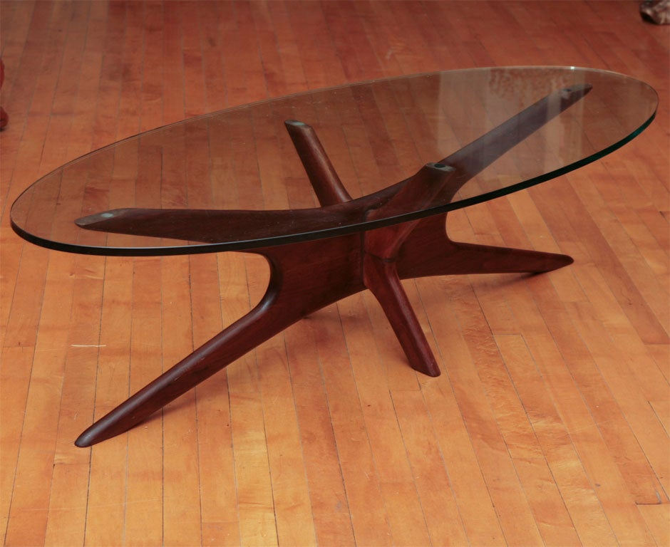 The atomic age walnut base of this mid cenury coffee table is of dramatic design and excellent constuction. The glass is vintage and is substantial in its size and thickness.