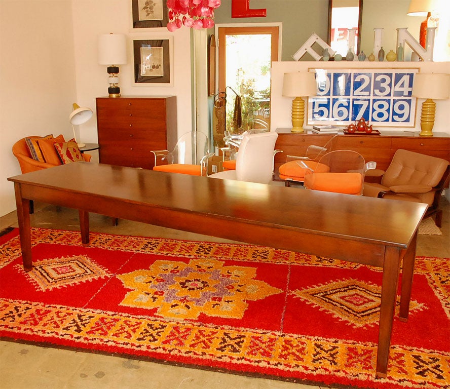 This handsome 1950's maple library table is long and narrow and has been restored and stained a medium walnut color. Can be used as a dining, conference, or library table.