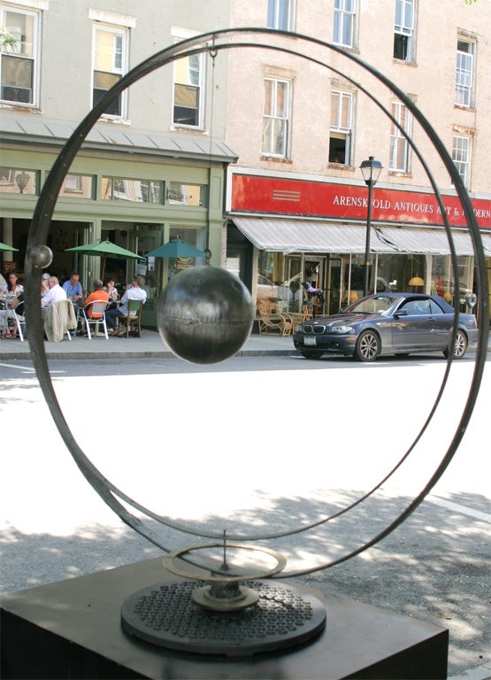Hanging sphere inside two hoops made from iron and tin on ring of copper on a metal base.    Measures 48