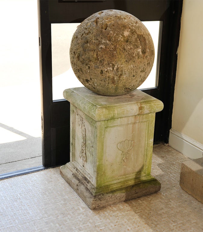 A Hand Carved Distressed Stone Ball With Traces of Moss Mounted on a Classic Stone Shaped Plinth with Paneled Sides Each Featuring a Classic Symbol on Stepped Base