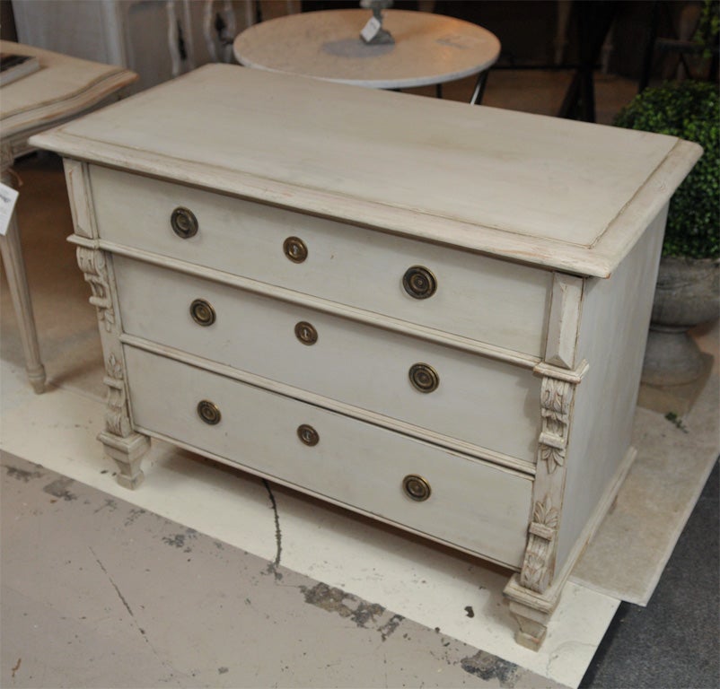 A beautiful creme peinte three-drawer commode with acanthus decoration standing on squared bulbous feet.