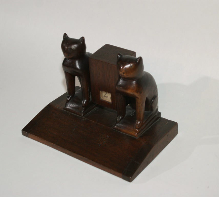 Finely carved sculptural figures on base in stained and varnished mahogany.  Rotating calendar box with dates.