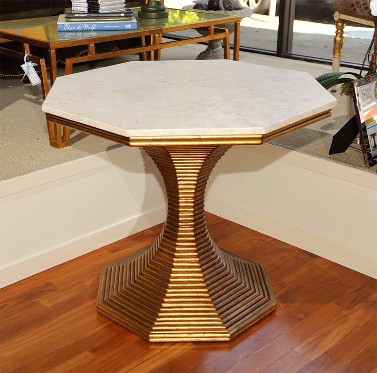Direct from BeeLine Home by Bunny Williams, this sensuous table with an hourglass figure is reminiscent of 1940’s Paris. An octagonal pedestal base of hand-applied reeded mahogany pieces finished in old gold patina support a honed, Tulung Agung