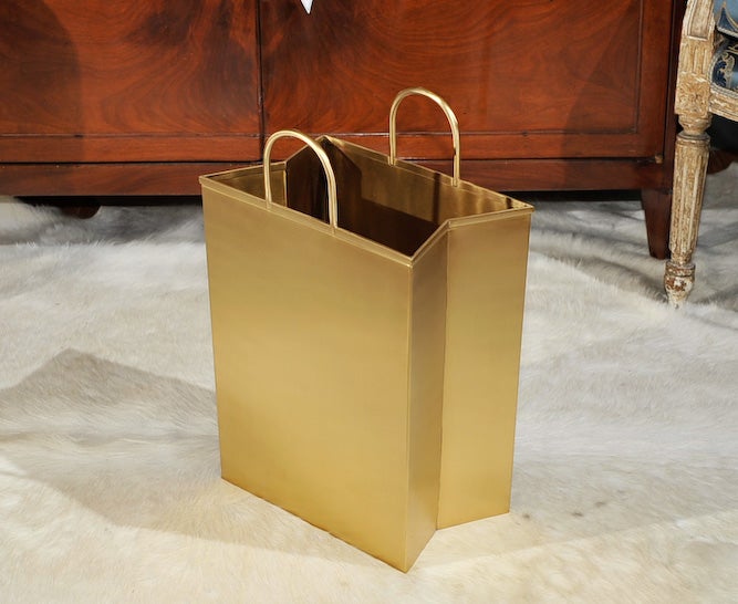 Direct from BeeLine Home by Bunny Williams, you can now throw your trash out in style with this unlacquered brass wastebasket in the form of a shopping bag with pinched sides and open demi-lune handles.