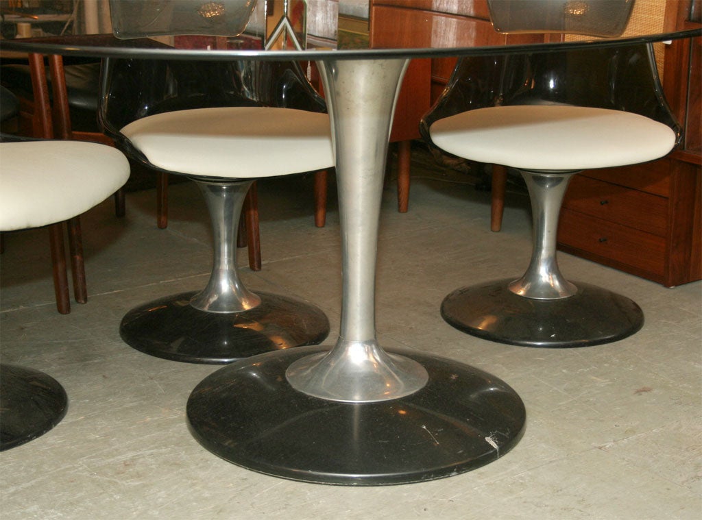 Table with smoked glass oval top over an aluminum base. The chairs are smoked lucite with an aluminum base and vinyl seats. Chairs measurements are: H: 35.25