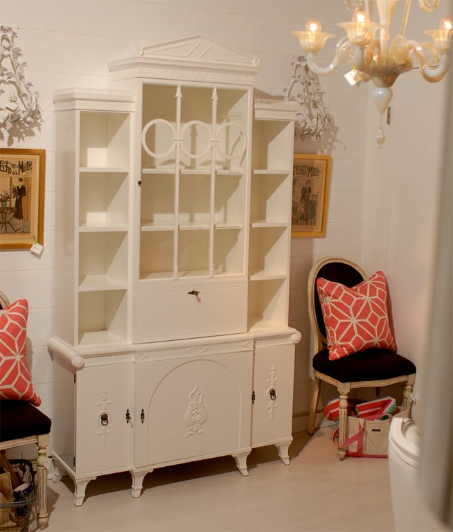 This is a vintage secretary with lots of detail.  Newly painted white semi gloss. Leaf detail on each top corner.  Greek key around the pediment.  Arrow and circle design on glass door.  Scroll on the base.  Fold down desk top.  Interior has