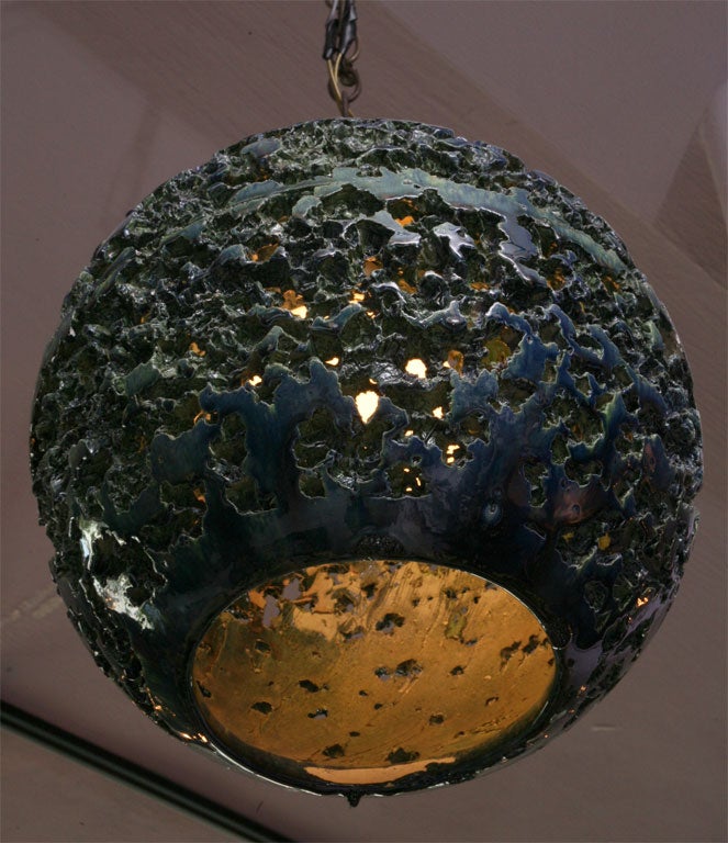 A very unusual glazed ceramic globe light fixture that has many see through areas. The color is a cool mix of greens and blues.