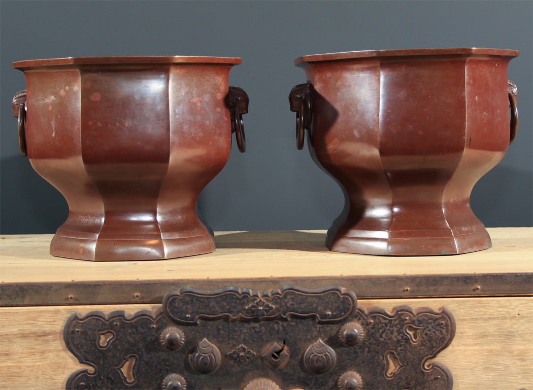 Pair of heavily cast bronze hibachi (brazier) used for hand warming and for brewing the occasional pot of tea. Over-all hexagonal form with unadorned straight sides and inset waist with tall flaring foot. The sides with two opposing well cast and