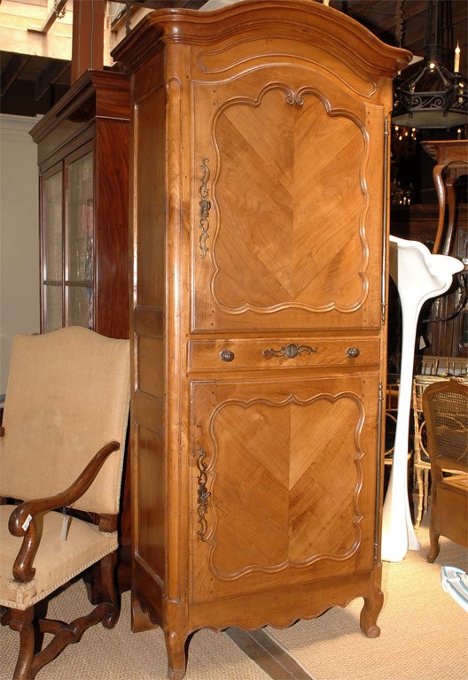 The arched cavetto molded and stepped cornice above triple paneled sides and two shaped panel door separated by a long drawer, the whole above carved scroll apron, with rounded paneled stiles continuing to short scrolled supports.