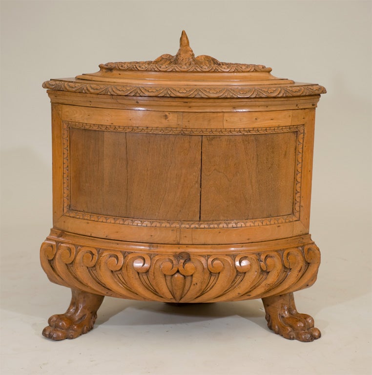 An early 19th century Italian Renaissance style walnut carved corner wine cooler; with a carved eagle lidded top supported by paw feet.