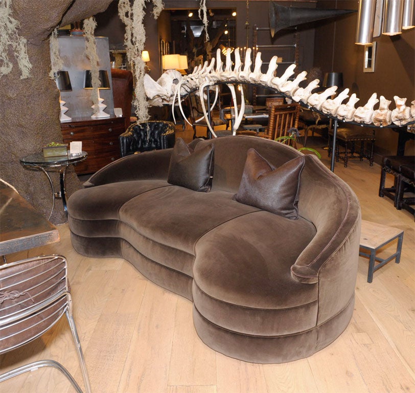 of dramtic serpentine exaggerated camel back<br />
modern kidney shaped, deep set environment<br />
with smooth, sloped padded arms<br />
upholstered in a Roger’s and Goffigan chocolate velvet <br />
double seamed seat with self welt