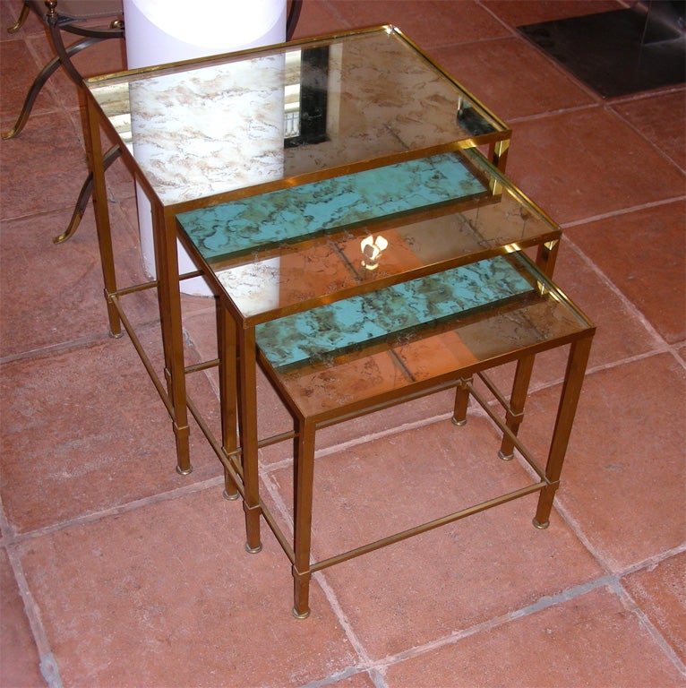 Three 1960s nesting tables in the style of Marc Duplantier with base in gilt bronze; top in distressed églomiséd mirror, probably not original. Middle table height 42.5 cm., length 45 cm., depth 30 cm. Smallest table: 37.5, 40, 25.