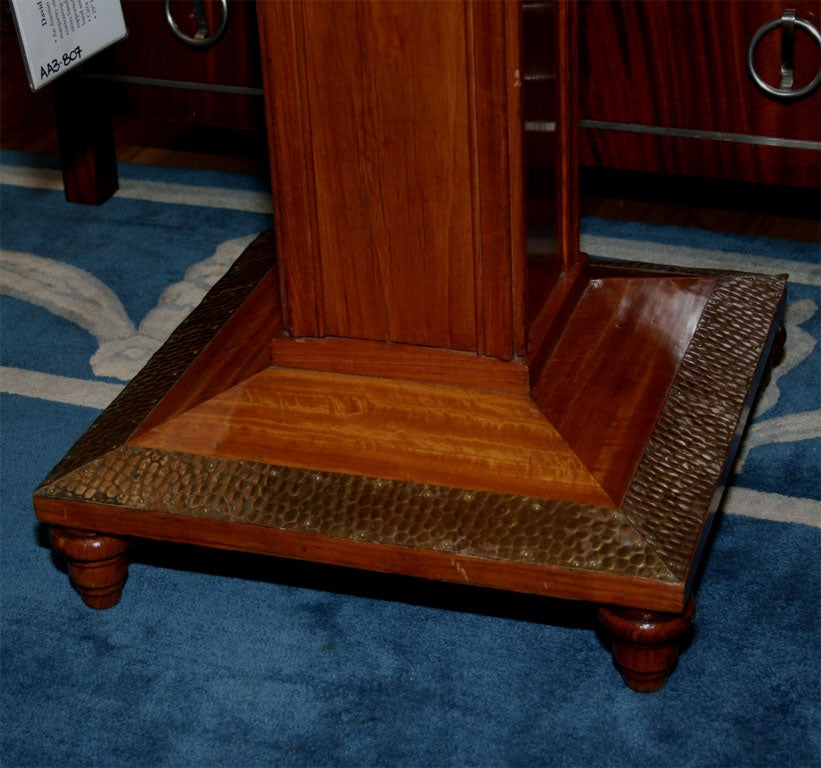 An Austrian side table with square top and marquetry stringing, having square top with contrasting veneered game tile surface with cross banding and square pedestal; supported by plinth, having repousee work band and with four bun feet.