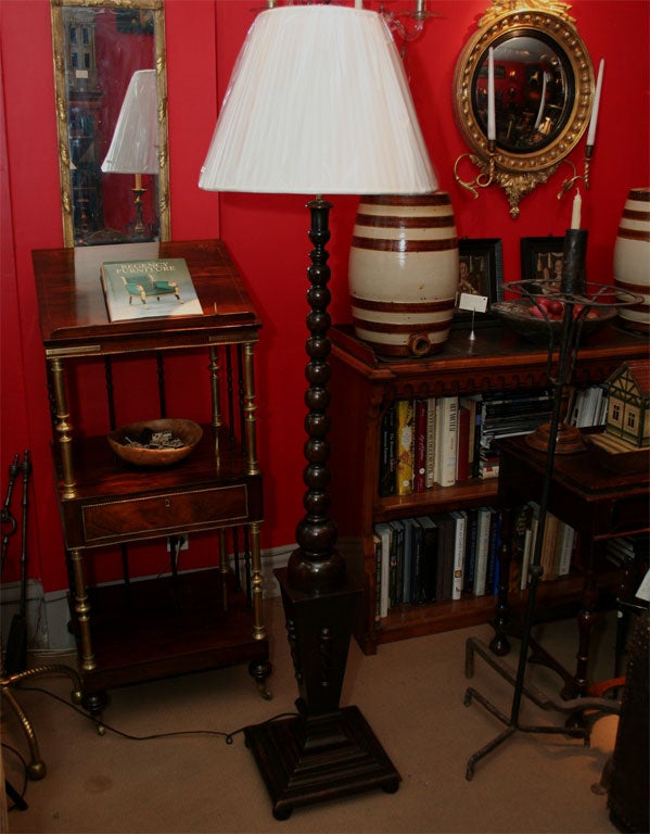 A floor lamp with tapering bobbin turned column over reverse tapered plinth with turned decorations on stepped base with ball feet.