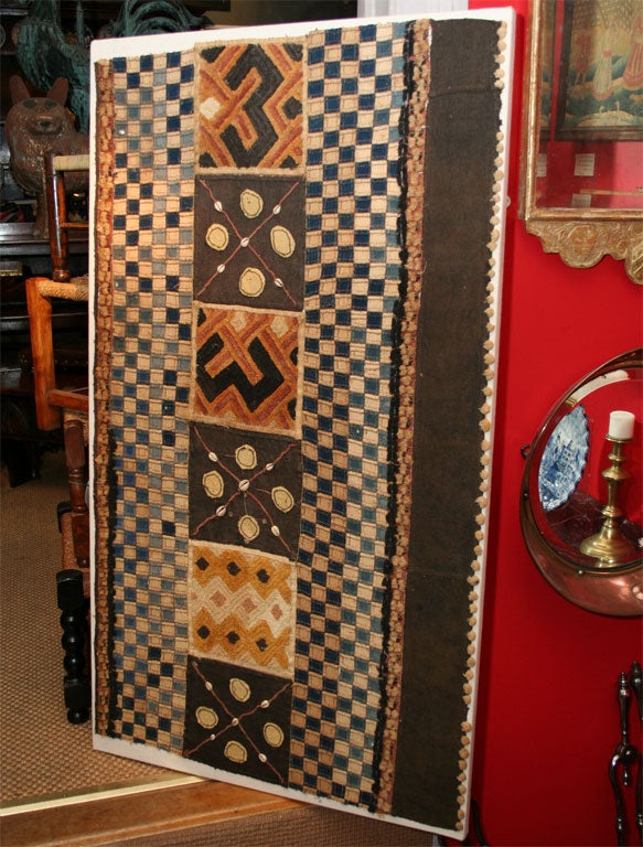 An African Kuba dance skirt made of hand woven squares on raffeta fabric made from the husks of coconuts, the dye handmade from indigo, detailing with real cowrie shells stitched in a decorative design.<br />
<br />
This cloth of quilted form