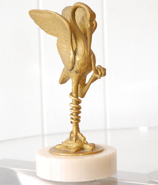 A gilt bronze Japanese sculpture of a graceful crane standing on a turtle grasping a snake. White marble base.