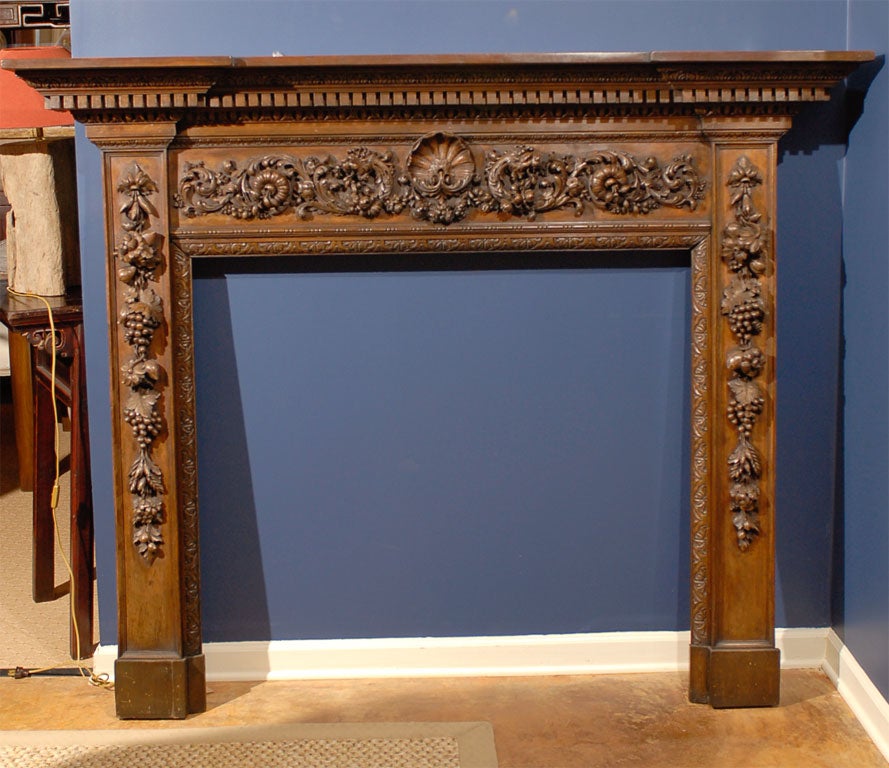 Remarkable 18th Century English early Georgian walnut mantel of the finest quality.  The carvings consist of a centered shell flanked by lions heads with flowers, vines and fruit, all in the manner of Grinling Gibbons.  All edges are carved with