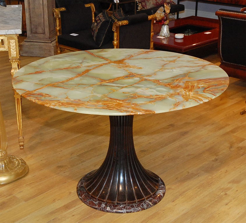 The large top over a fluted and spreading wood standard on a marble circular base.