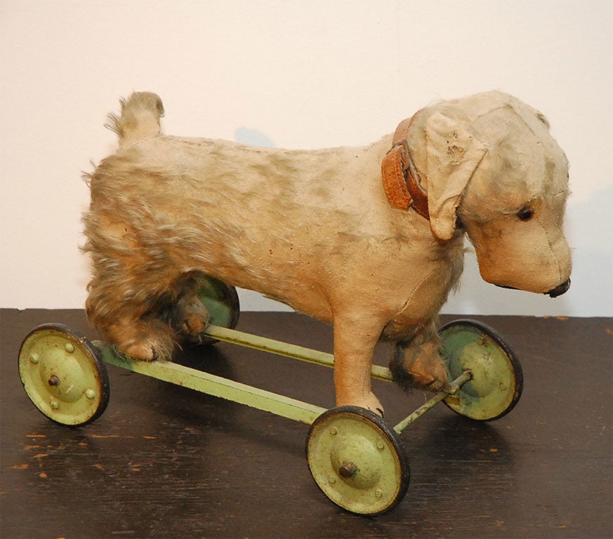 1920'S STUFFED DOG ON WHEELS WITH ORIGINAL COLLAR AND ORIGINAL METAL WHEELS WITH GLASS EYES.