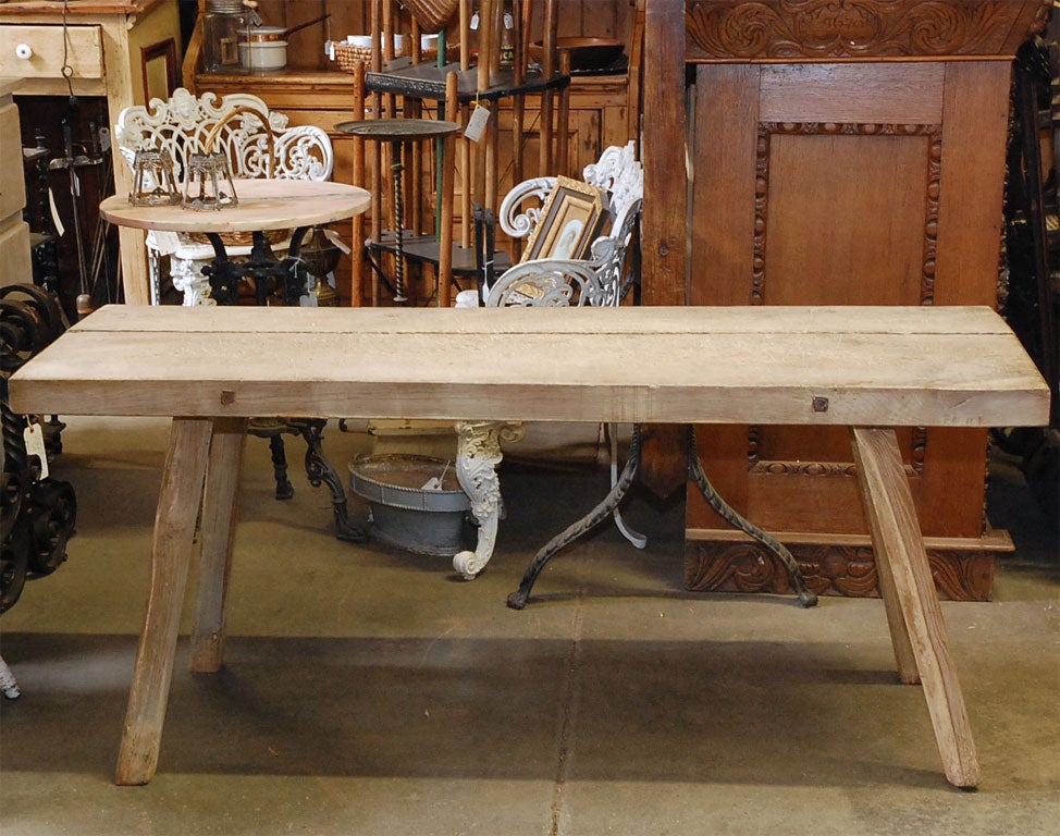 A boldly formed old work table, circa 1900, standing on four square splayed legs. The wood shows a white luster finish, probably from being washed and dried in the sun. A good piece for the right setting.