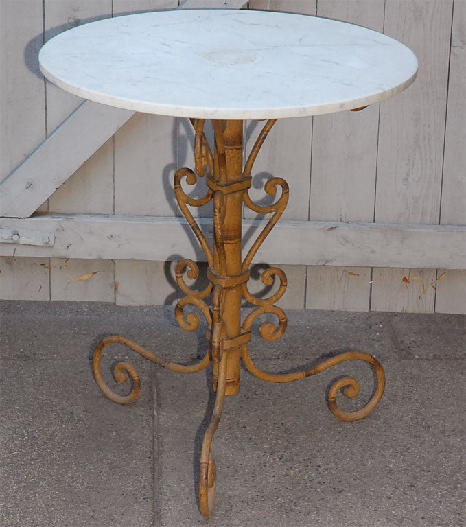 A lovely garden or end table with a marble top on a painted faux bamboo iron work base.