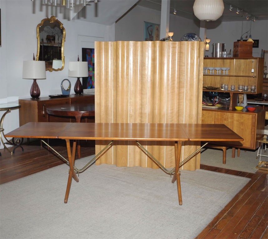 Hans Wegner design dining table for Andreas Tuck. Made with a teak drop-leaf top on oak scissor legs with brass supports. Completely restored, and signed. Net $5400.00