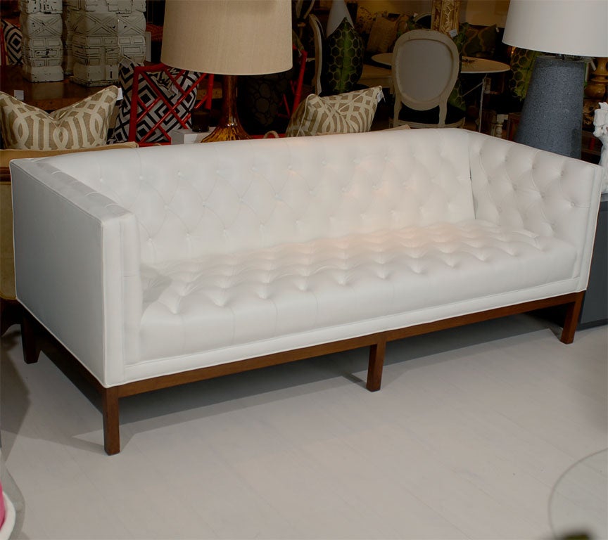This is a vintage sofa with the original wood base existing finish.  Newly upholstered in white high-end leather. Original diamond tufted style.  Unique tuxedo style sofa.