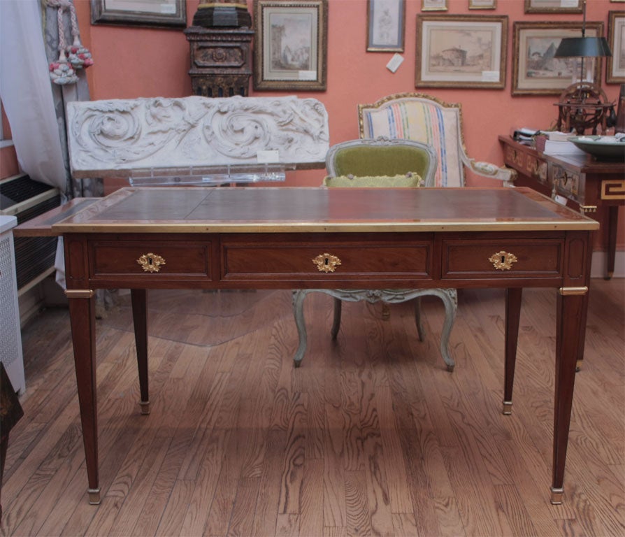 This desk has a rectangular gilt and tooled brown leather-inset top with molded surround. Each side has a writing slide above a three-paneled frieze of drawers with cartouche-shaped, scrolled, laurel and berry keyhole mount, reversing to three faux
