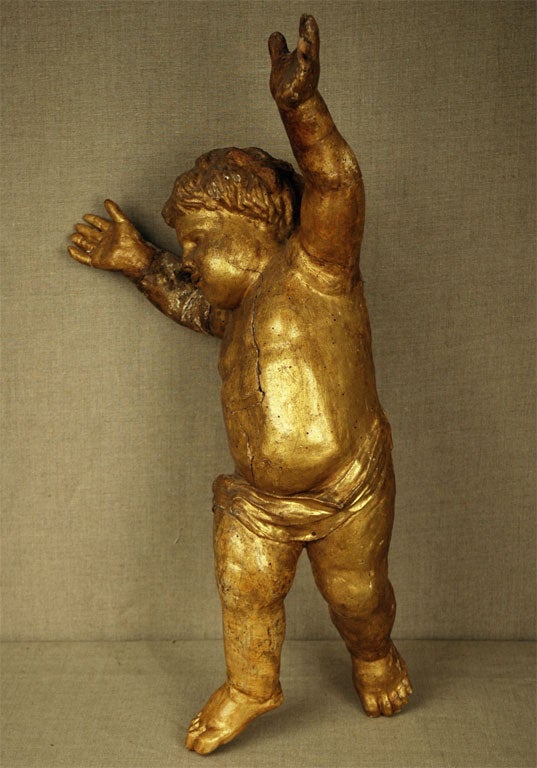 Handgeschnitzte, handvergoldete Holzstatue eines Cherubs, der seine Hände zum Himmel streckt.
